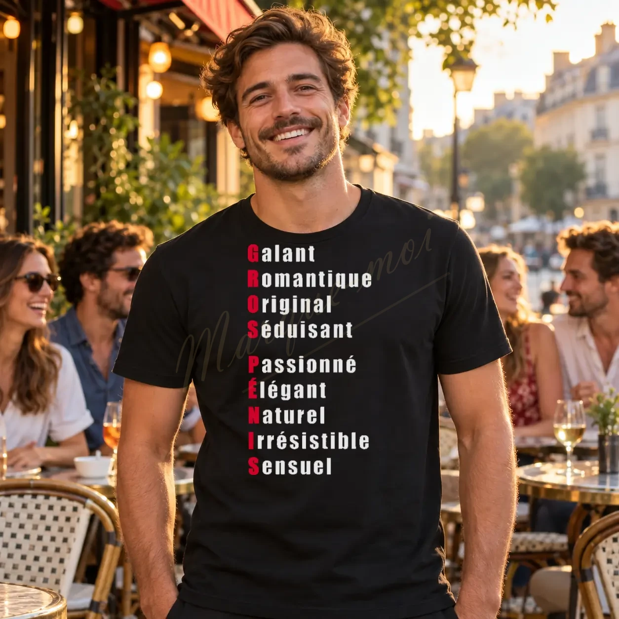 Homme en terrasse portant un tee-shirt noir avec l’acrostiche humoristique « GROS PÉNIS » aux initiales rouges sur le devant.