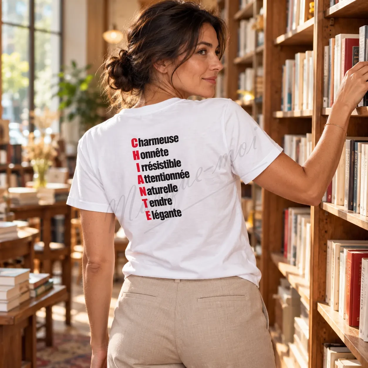 Femme portant un t-shirt blanc avec l’acrostiche « CHIANTE » noir et rouge au dos, devant une étagère de livres.