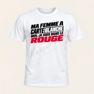T-shirt blanc vu de face avec le slogan « Ma femme a carte blanche, moi je suis dans le rouge » en typographie noire et rouge, sur fond beige.